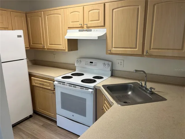 a kitchen with granite countertop a sink stove and refrigerator