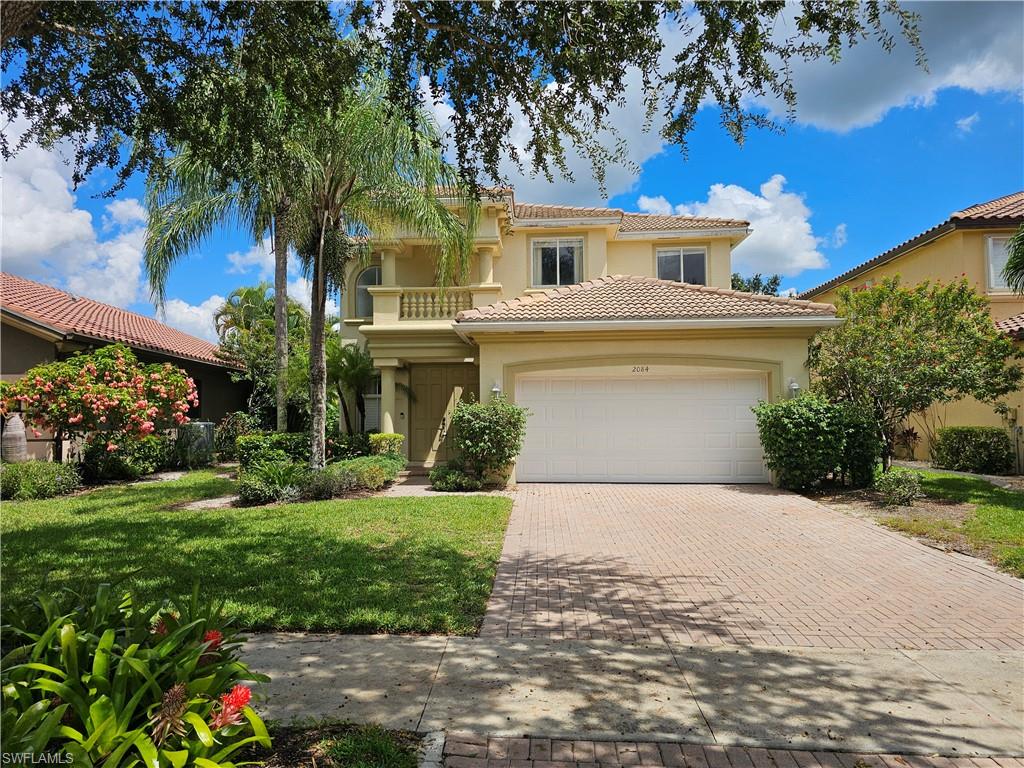 Mediterranean / spanish-style house with decorative driveway, stucco siding, a tiled roof, a front lawn, and a balcony