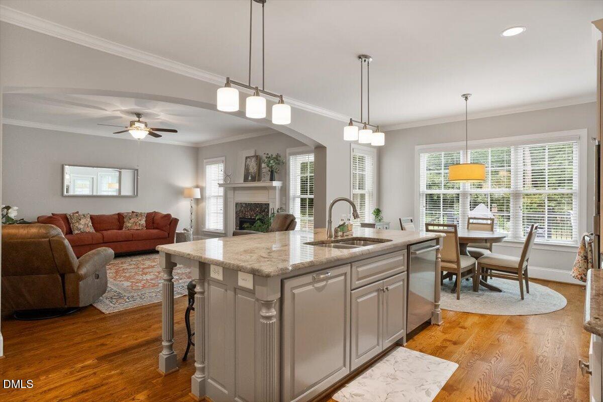 1404 Ivy Lane Raleigh, NC 27609 - Photo 11 of 37 Open-concept living area with wood-finish flooring, a kitchen island with integrated sink, stainless steel appliances, and an arched entryway