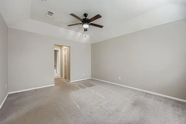 an empty room with a ceiling fan and windows
