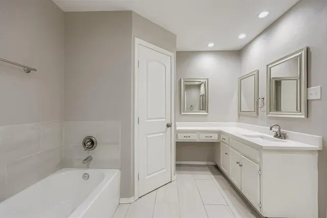 a spacious bathroom with a bathtub sink and mirror