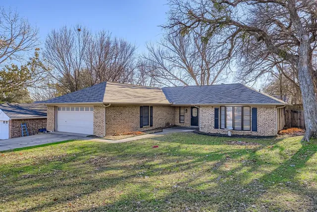 a view of a house with a yard and large tree