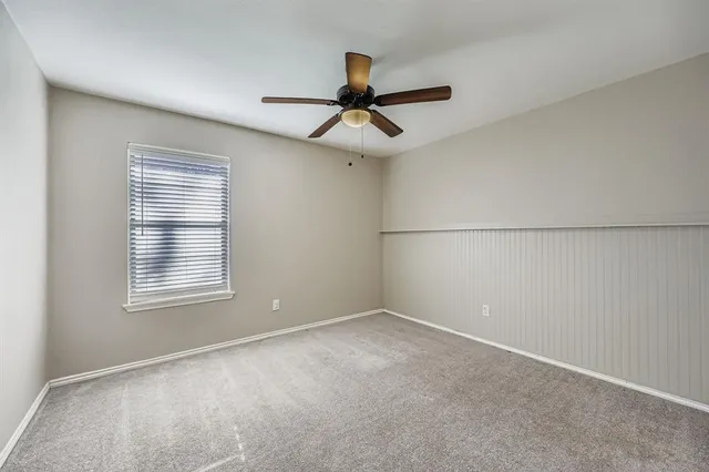 an empty room with a window and a ceiling fan