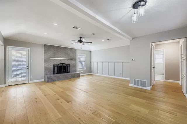 a view of empty room with wooden floor and fireplace