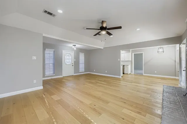 a view of empty room with wooden floor and ceiling fan