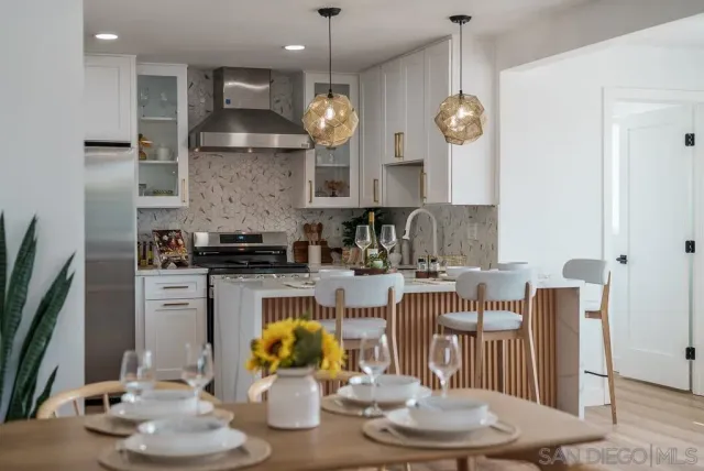 a kitchen with stainless steel appliances kitchen island granite countertop a dining table chairs and a refrigerator