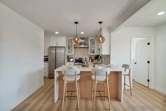 a kitchen with stainless steel appliances granite countertop a sink dishwasher a stove a refrigerator a dining table and chairs with wooden floor