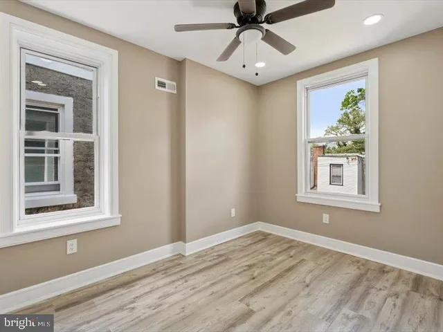 a view of an empty room with a window and wooden floor