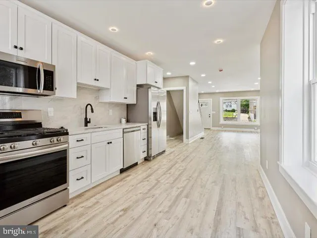 a kitchen with stainless steel appliances granite countertop a stove a sink and white cabinets
