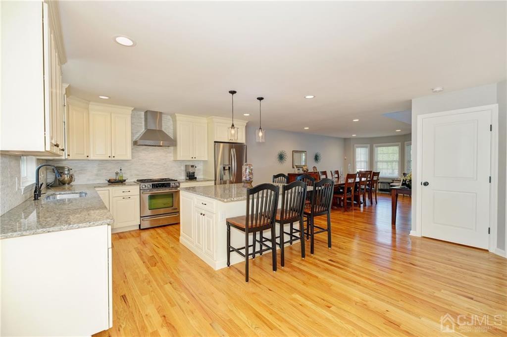 341 Dunellen Avenue Dunellen, NJ 08812 - Photo 6 of 24 a kitchen with stainless steel appliances granite countertop a stove top oven a dining table and chairs with wooden floor