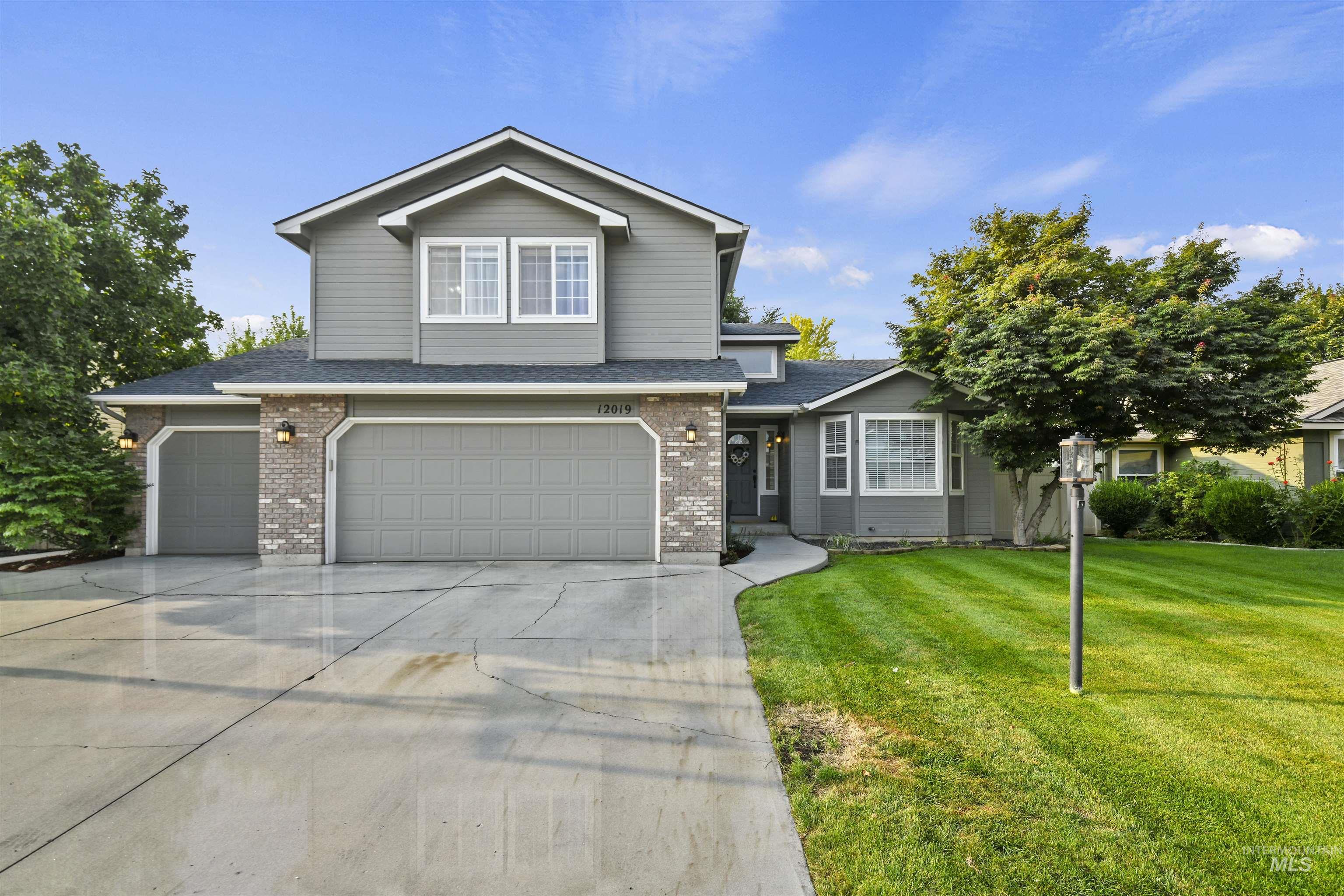 12019 West Rader Drive Boise, ID 83713 - Photo 2 of 41 Traditional-style house with driveway, a garage, a front lawn, roof with shingles, and brick siding