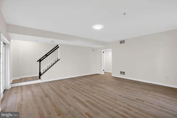 a view of an empty room with wooden floor and stairs