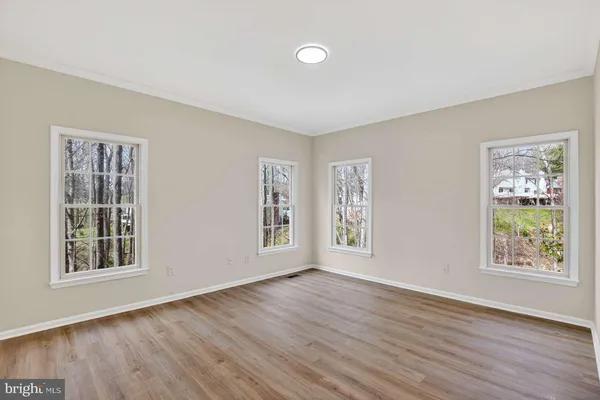 a view of an empty room with wooden floor and window
