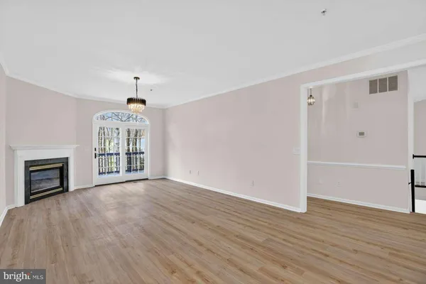 a view of an empty room with wooden floor fireplace and a window