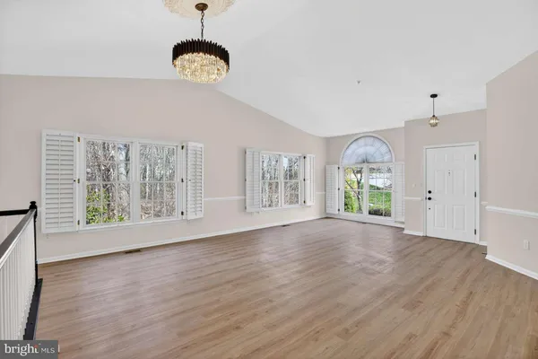 a view of an empty room with wooden floor and window