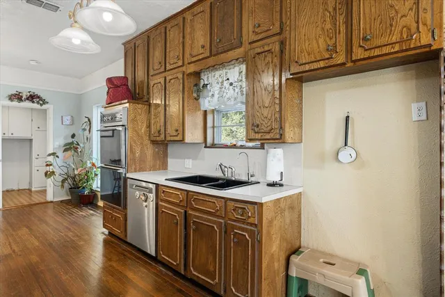 a kitchen with stainless steel appliances granite countertop a sink cabinets and wooden floor