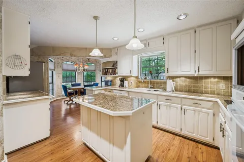 a kitchen with stainless steel appliances granite countertop a sink a stove and a wooden floors