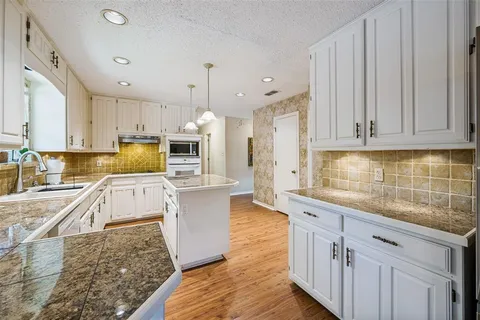 a large kitchen with stainless steel appliances granite countertop a lot of counter space and wooden floors