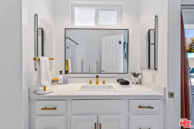 a bathroom with a sink and a mirror white cabinets