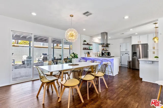 a view of a dining room and livingroom with furniture wooden floor a chandelier