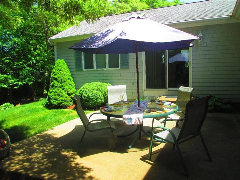 52 Thread Needle Lane Centerville, MA 02632 - Photo 22 of 32 a patio with a table and chairs under an umbrella