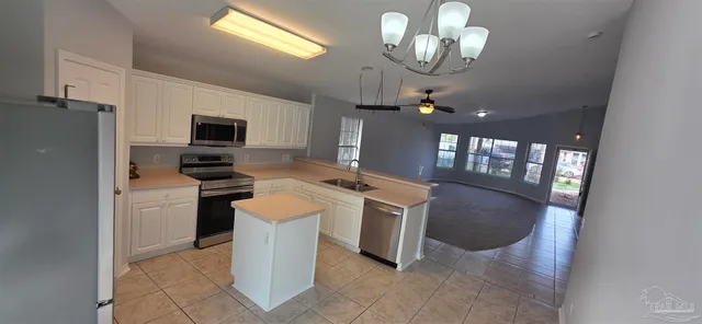 a kitchen with a chandelier stainless steel appliances cabinets and furniture