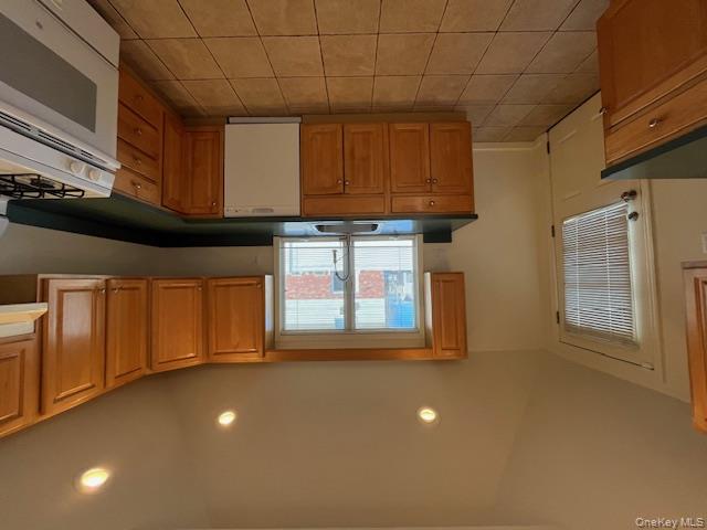 46 Firwood Road, Unit 1 Port Washington, NY 11050 - Photo 5 of 16 Kitchen with range, vaulted ceiling, dark countertops, dishwasher, and light tile patterned floors