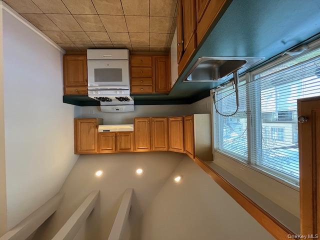 46 Firwood Road, Unit 1 Port Washington, NY 11050 - Photo 6 of 16 Kitchen with range, dark countertops, light tile patterned floors, extractor fan, and lofted ceiling