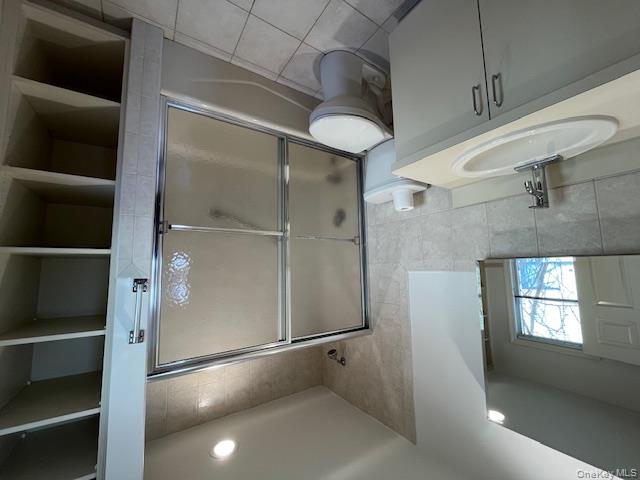 46 Firwood Road, Unit 1 Port Washington, NY 11050 - Photo 10 of 16 Full bath with tile walls, vanity, bath / shower combo with glass door, light tile patterned floors, and recessed lighting