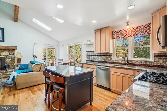 a kitchen with stainless steel appliances granite countertop a sink dishwasher a stove and a refrigerator with wooden floor