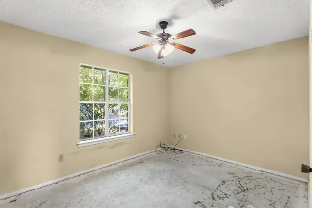 an empty room with windows and fan