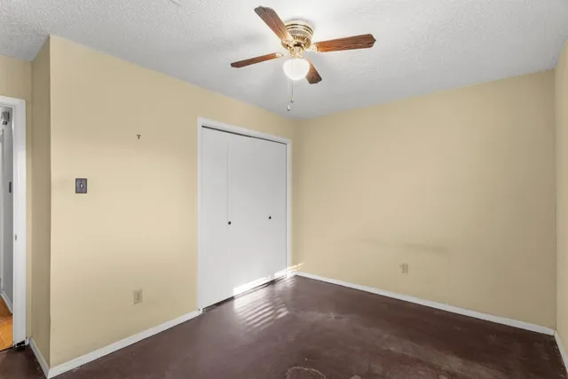 an empty room with a window and a fan