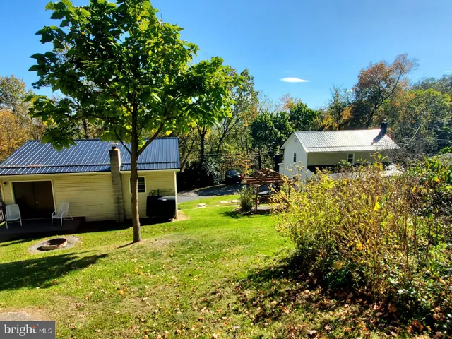 a backyard of a house with table and chairs under an umbrella
