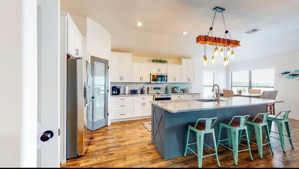 a kitchen with stainless steel appliances kitchen island granite countertop a table chairs and a refrigerator
