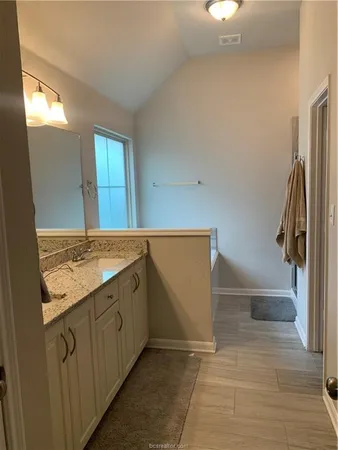 a bathroom with a granite countertop sink a toilet and a tub