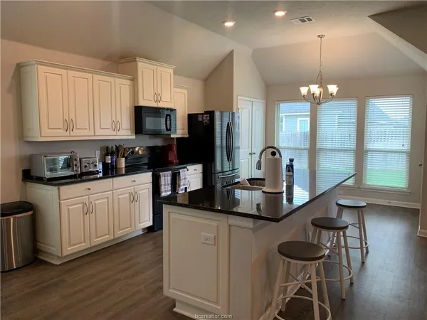 a kitchen with kitchen island granite countertop a sink cabinets and wooden floor