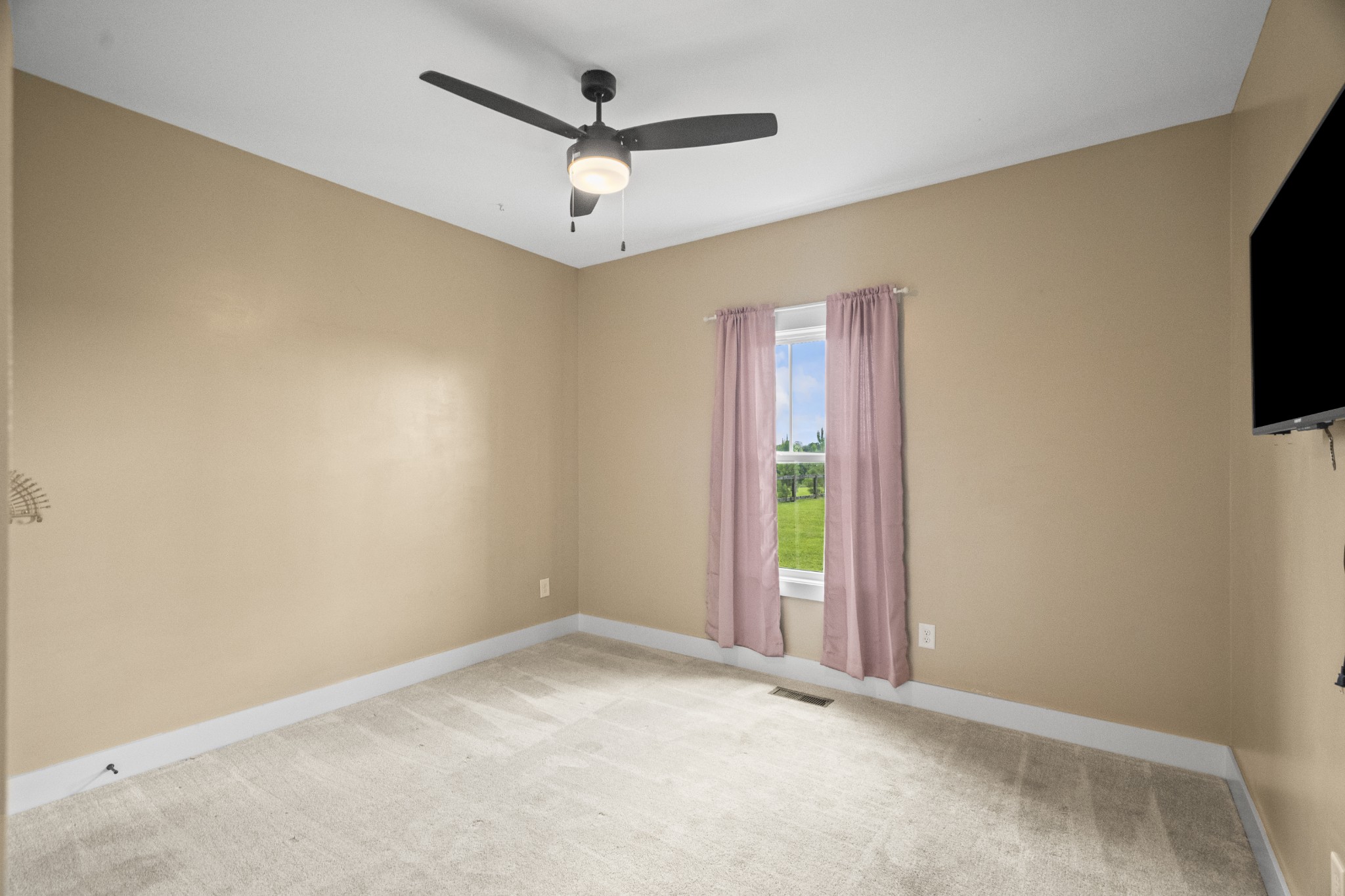 1406 Fowler Ford Road Portland, TN 37148 - Photo 32 of 54 an empty room with a flat screen tv and a ceiling fan