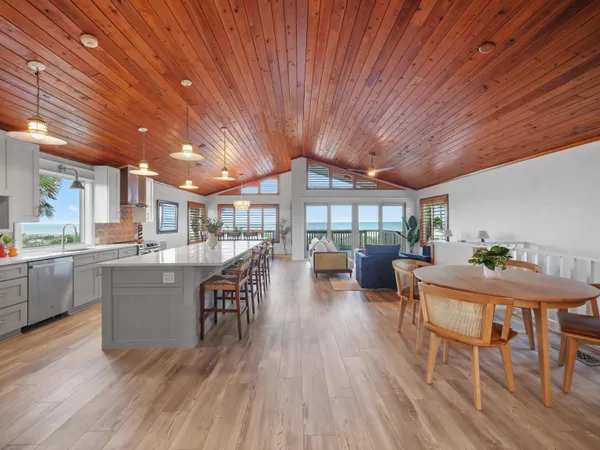 a open kitchen with stainless steel appliances granite countertop a table chairs stove and wooden floor