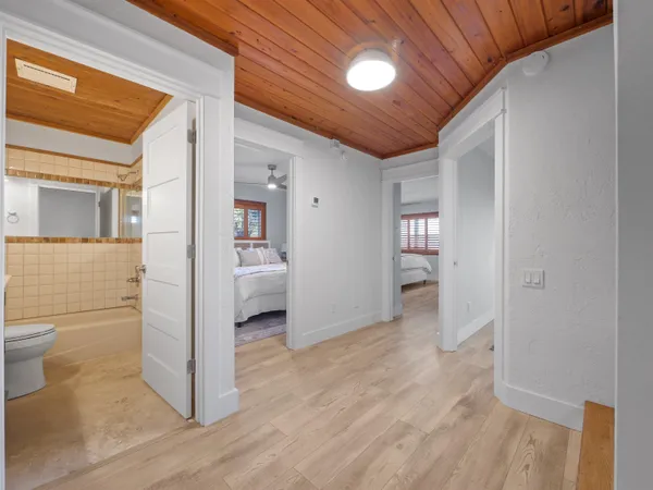 a view of a hallway with wooden floor and a bathroom