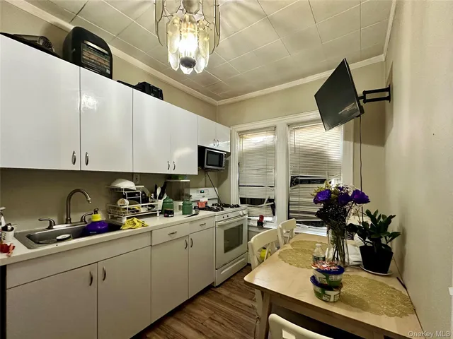 a kitchen with a sink dishwasher and white cabinets with wooden floor