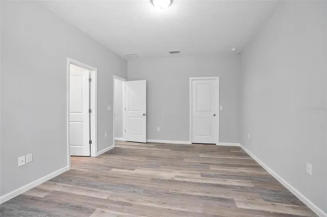 an empty room with wooden floor cabinet and windows