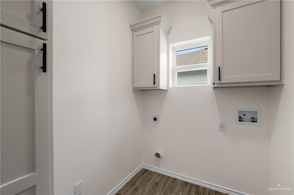 18054 Spruce Street Combes, TX 78552 - Photo 10 of 25 Utility room featuring wood-finish flooring, white cabinetry with black hardware, and a window for natural light