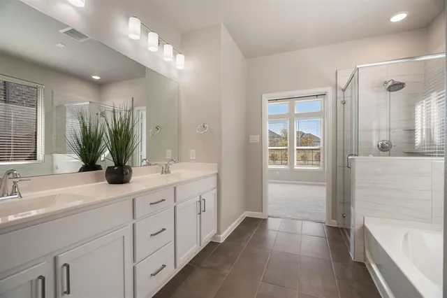 a bathroom with a double vanity sink a large mirror a bathtub and next to a window