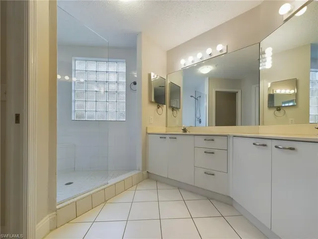 a spacious bathroom with a shower a sink and a mirror