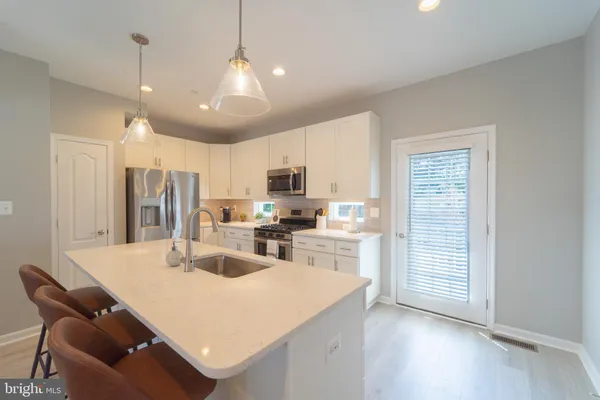 a kitchen with stainless steel appliances kitchen island granite countertop a sink dishwasher a stove a refrigerator and a dining table with wooden floor