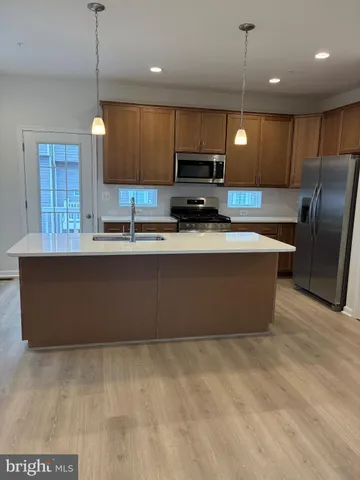 a large kitchen with kitchen island a large counter top stainless steel appliances and cabinets