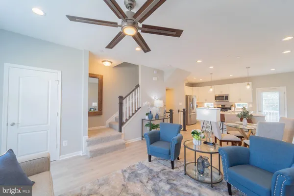 a living room with furniture kitchen view and a wooden floor