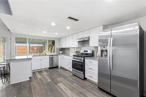 a kitchen with granite countertop a refrigerator stove top oven and sink