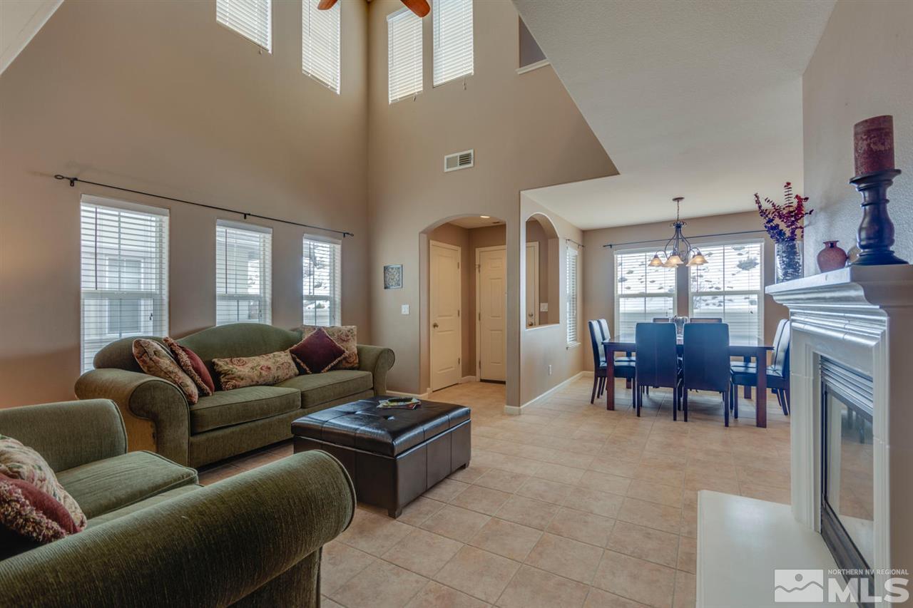 7660 Stone Bluff Way Reno, NV 89523 - Photo 9 of 22 a living room with furniture a fireplace and a dining table with wooden floor
