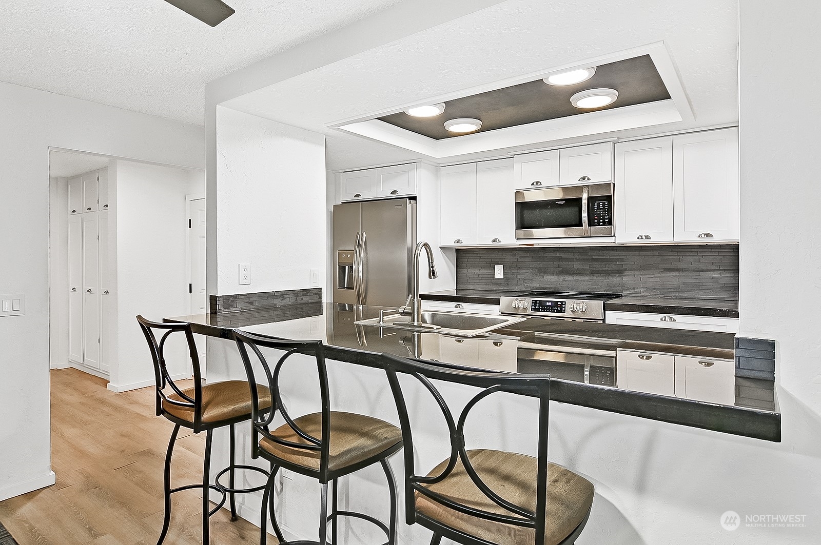14401 Southeast Petrovitsky Road, Unit D105 Renton, WA 98058 - Photo 5 of 25 a kitchen with stainless steel appliances kitchen island a table chairs in it and a microwave
